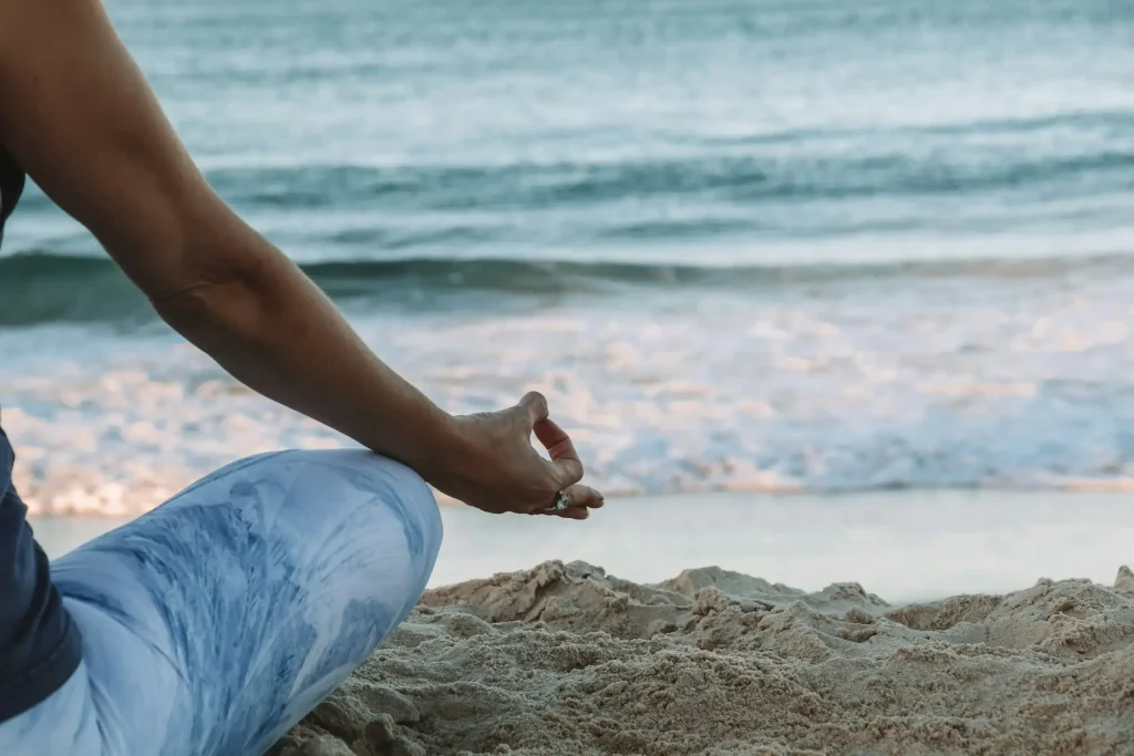 Frau sitzt achtsam am Strand – Meditation und Loslassen beim exklusiven Einzel-Retreat.